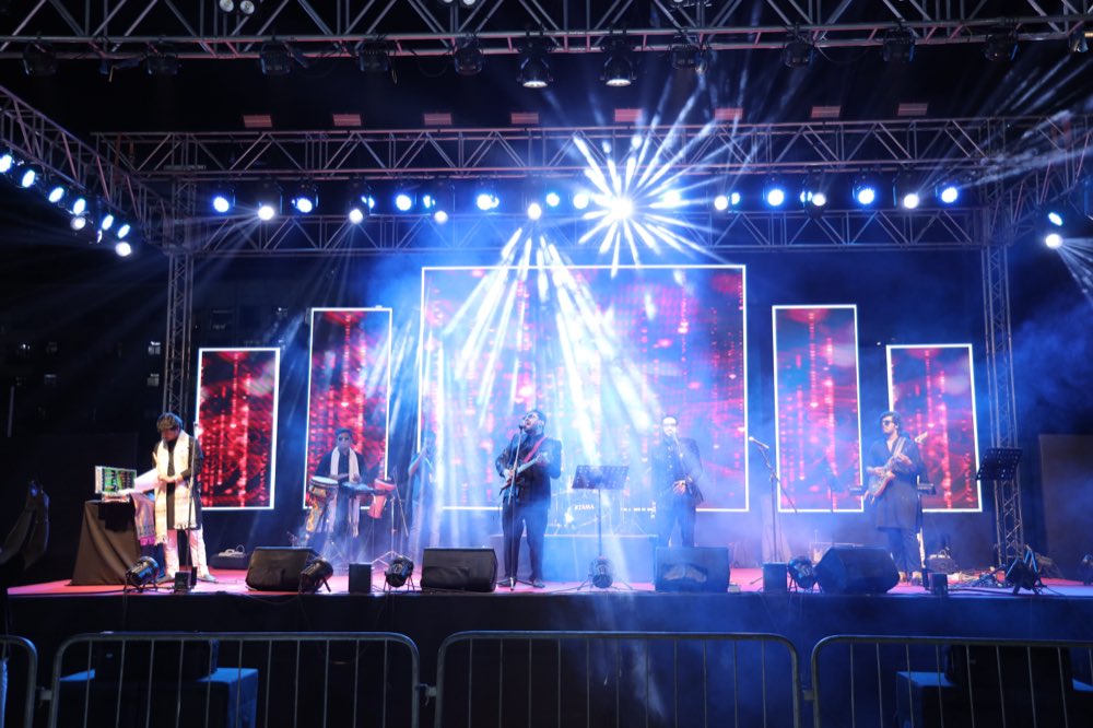 The full band across a concert stage under blue and white lighting